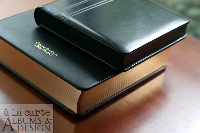 large traditional matted album in black Gramercy leather and gold gilding; medium traditional matted album in black leatherette with line cover detail and black gilding.